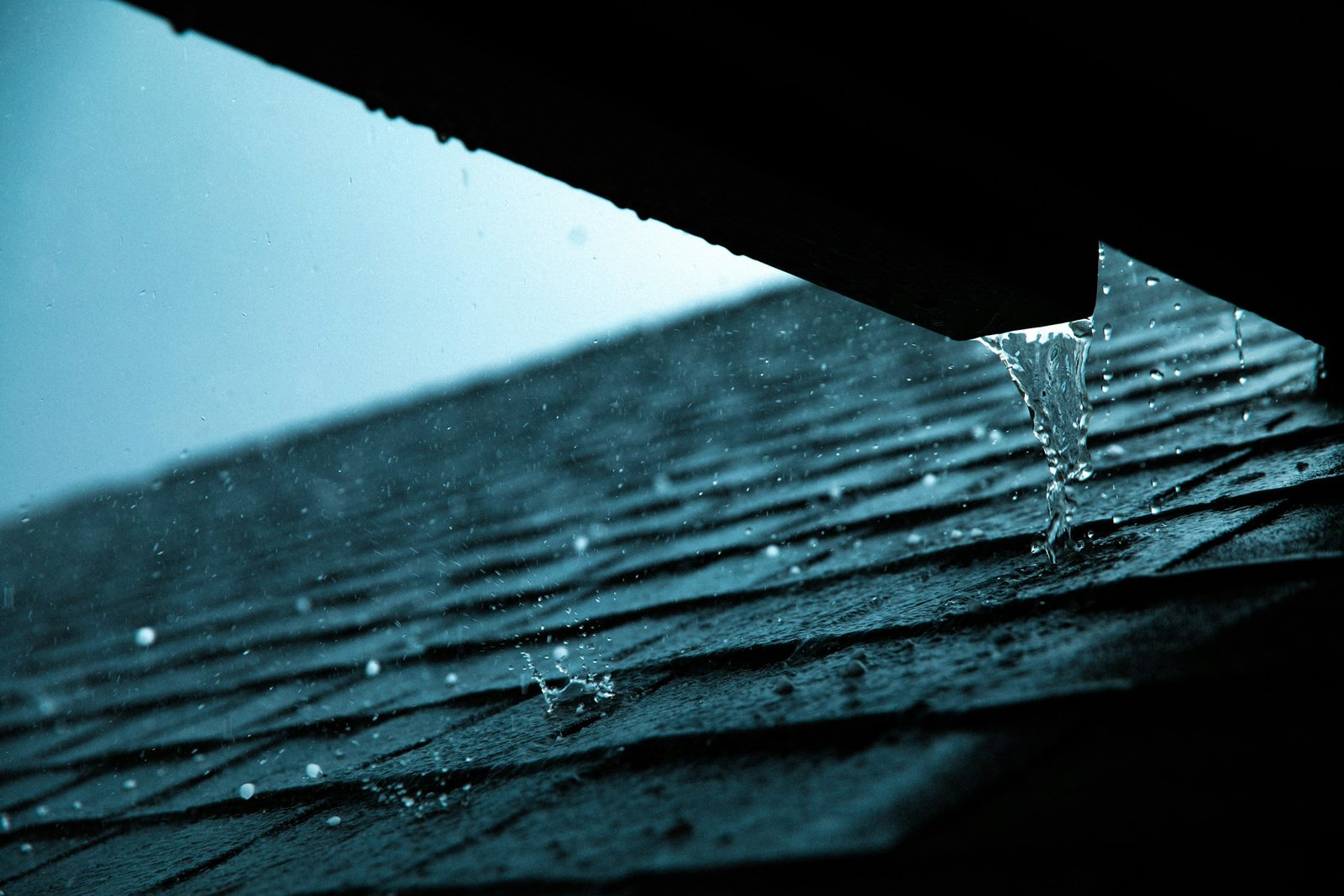 A gutter and downspout at a building roof edge